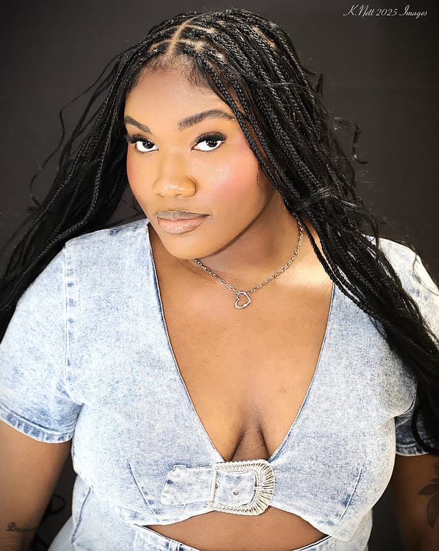 A client wearing long black knotless braids past the shoulder, with clean parting across the crown.