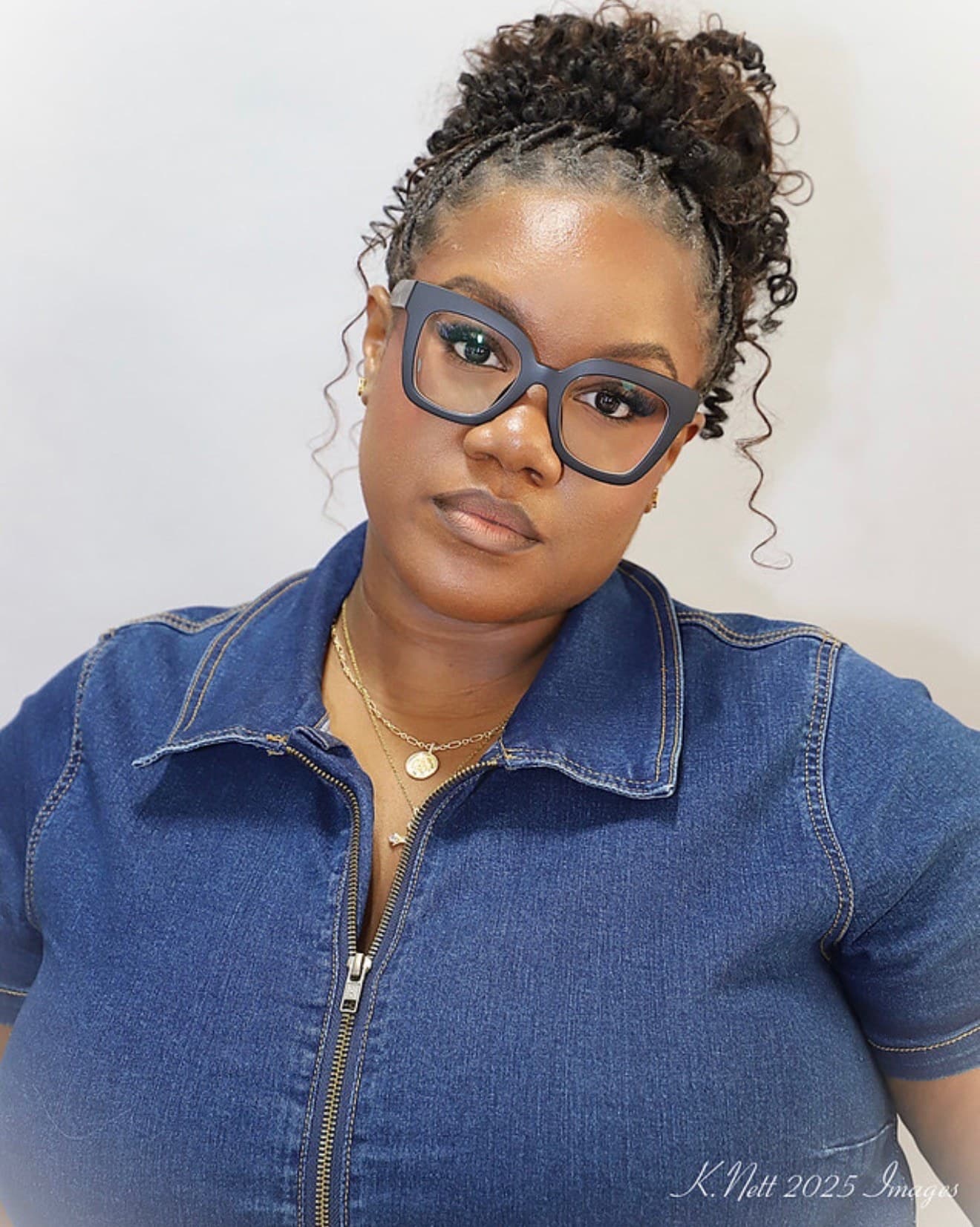A client wearing her natural hair in a braided updo, flat braids across the front gathered into a curly crown, with curls left loose at the temples.